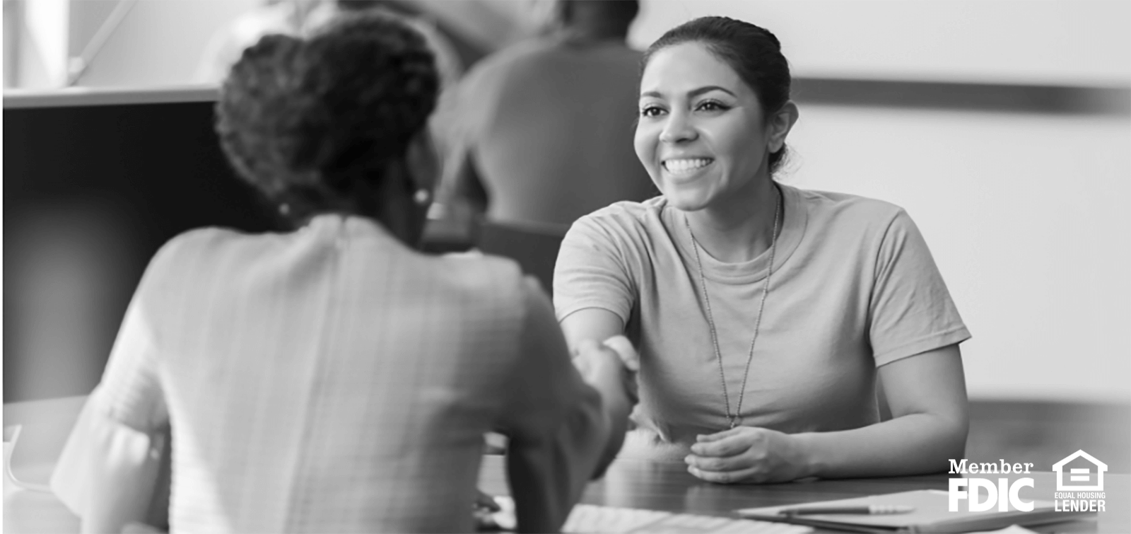 two women shake hands after finishing loan paperwork