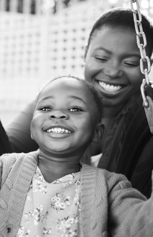 Mother and daughter outside playing on a swing set