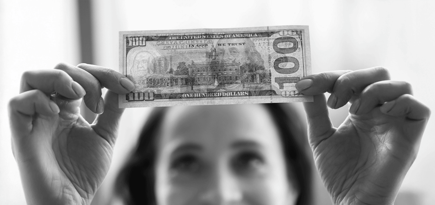 Woman checking to see if a $100 bill is real