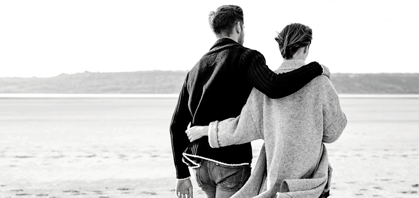 a military couple walks down a beach
