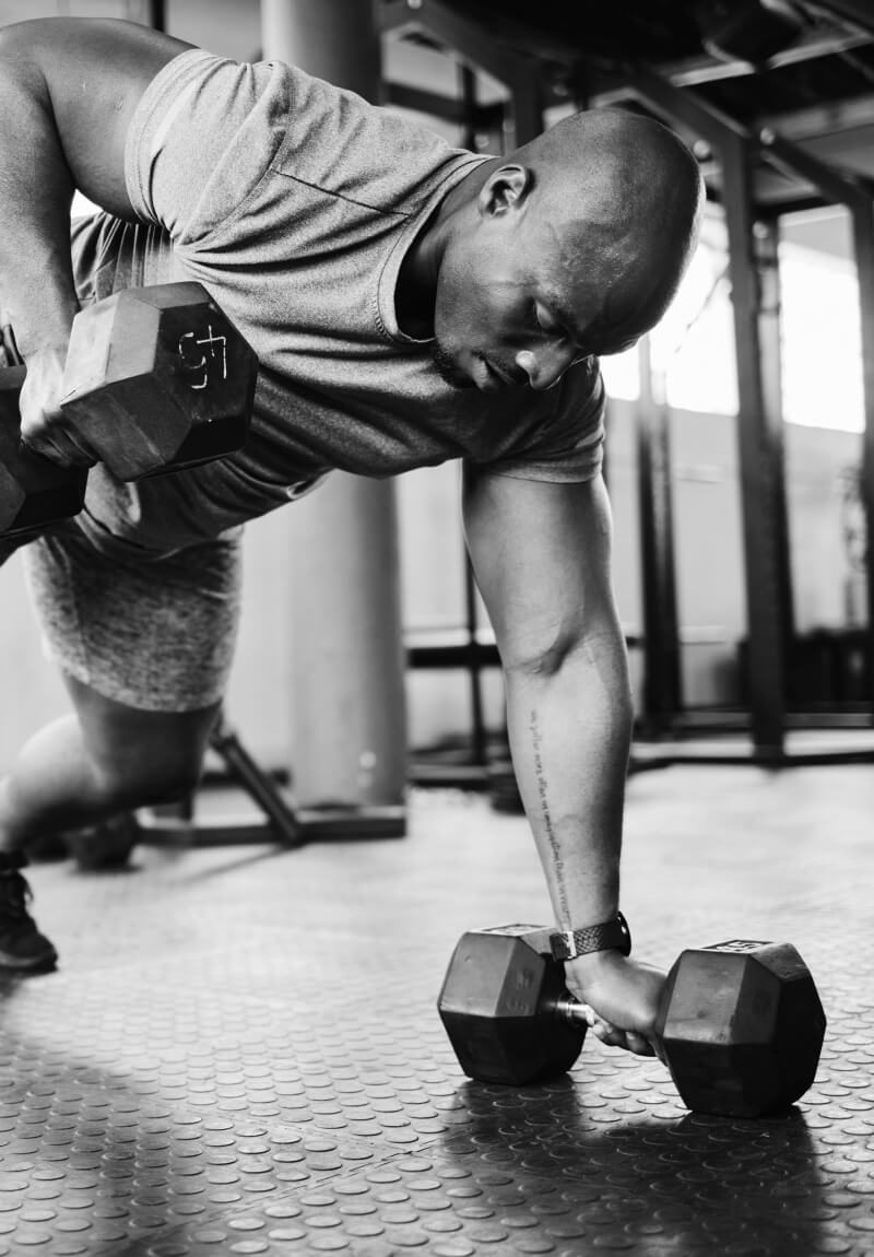 Man in gym lifting weights in plank position