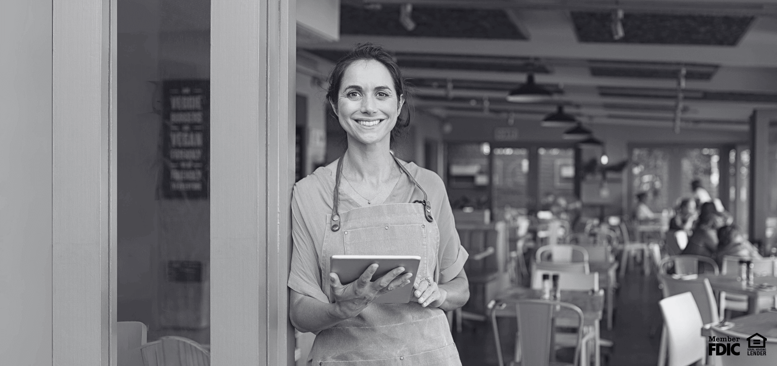a young woman stands outside her business while checking her business checking account on online banking.
