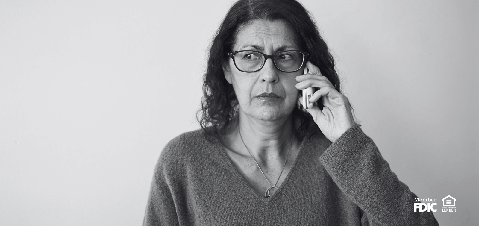 Woman looks scared and confused while speaking to phone call scammers on her cell phone.