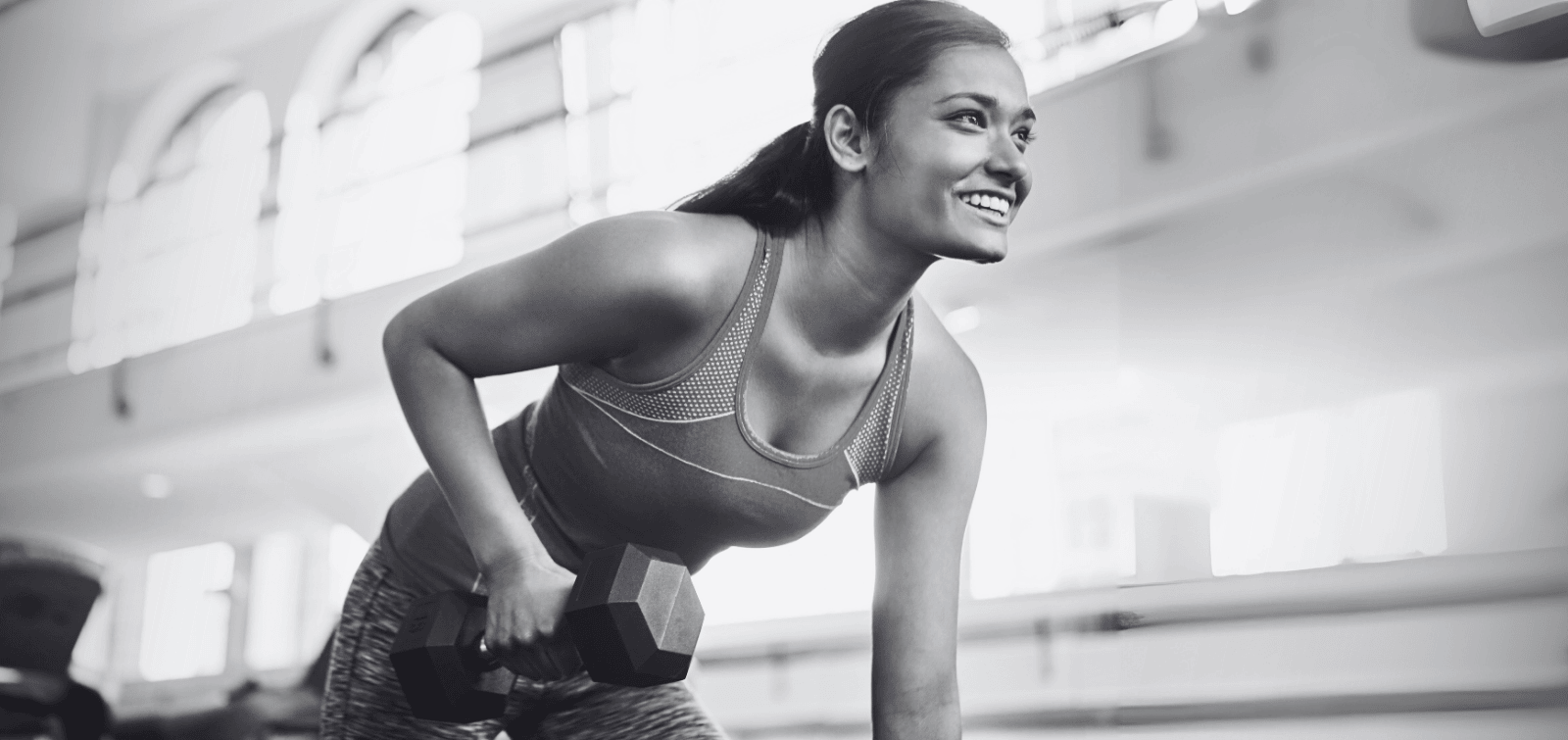 Happy woman lifting weights at the gym.