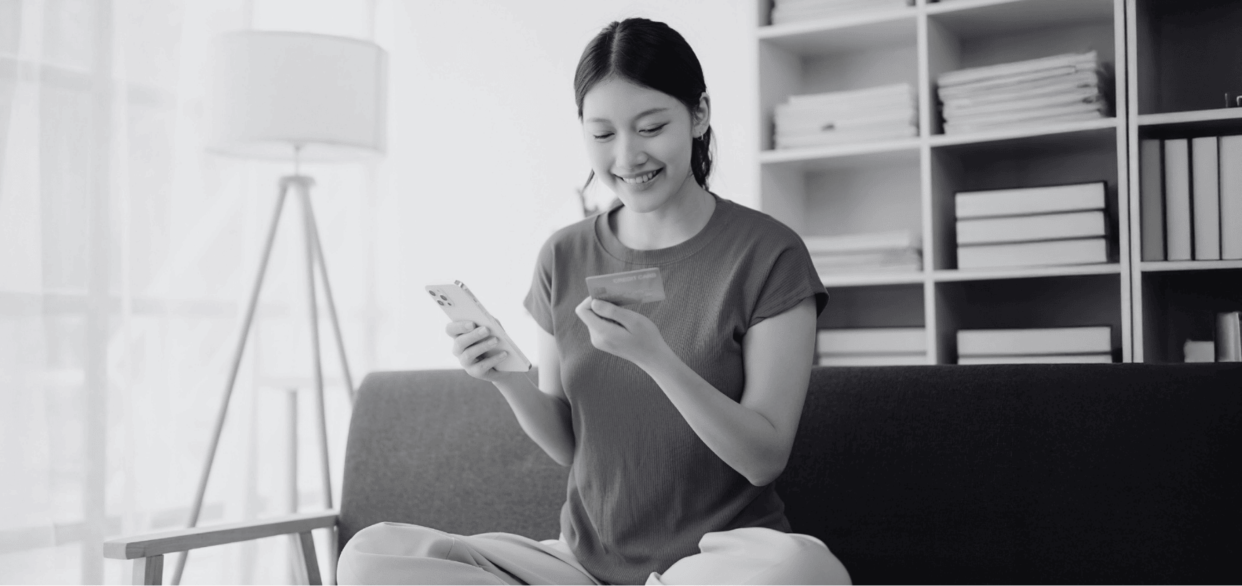 Woman looking at her checking account debit card for an online transaction.